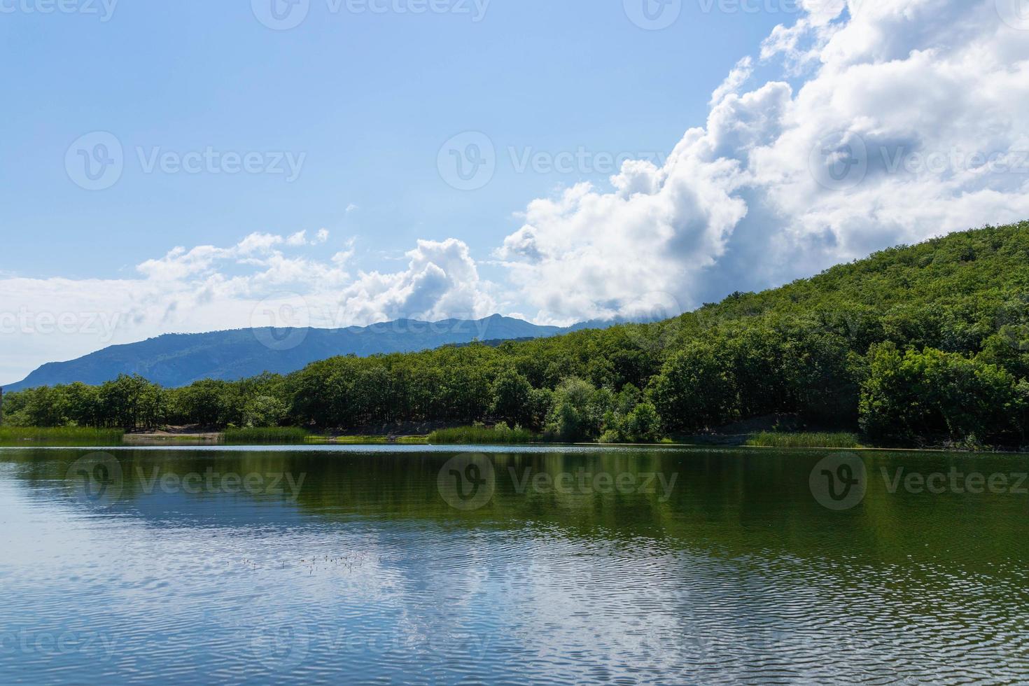 Mountains surround the mountain lake. The surface of the lake reflects sunlight. Landscape photo