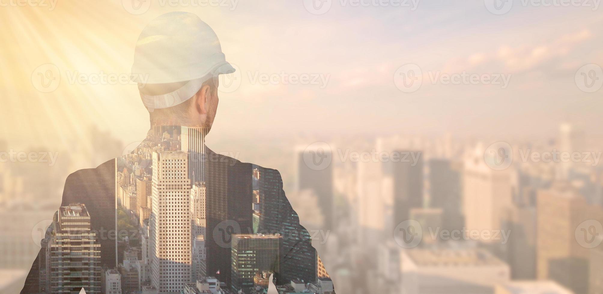 Double exposure of an engineer in a protective helmet against the background of the city, metropolis. photo
