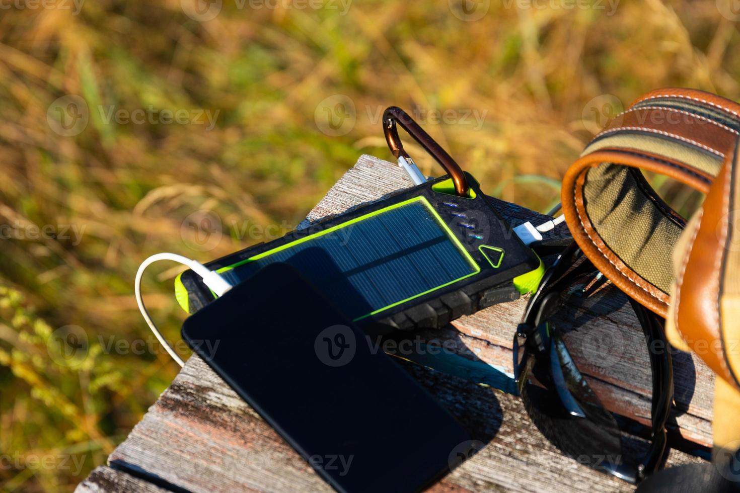 Solar energy battery device, power bank and telephone on a wooden table with a backpack. Solar charge your smartphone. Selective focus photo