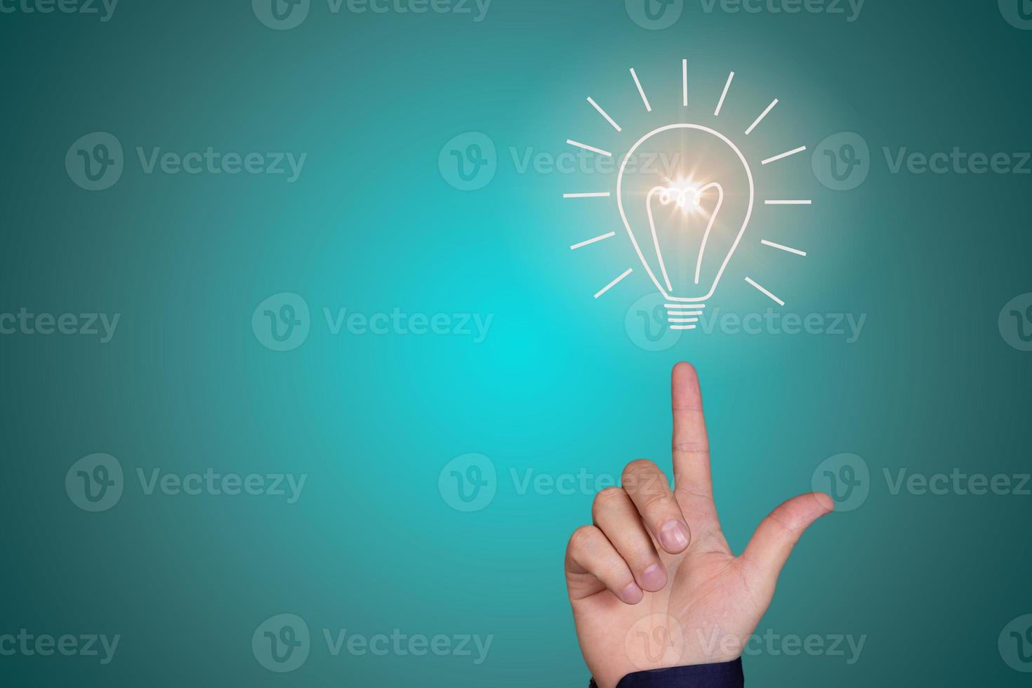 Light bulb on the fingertip of a man's hand on a blue-green background photo