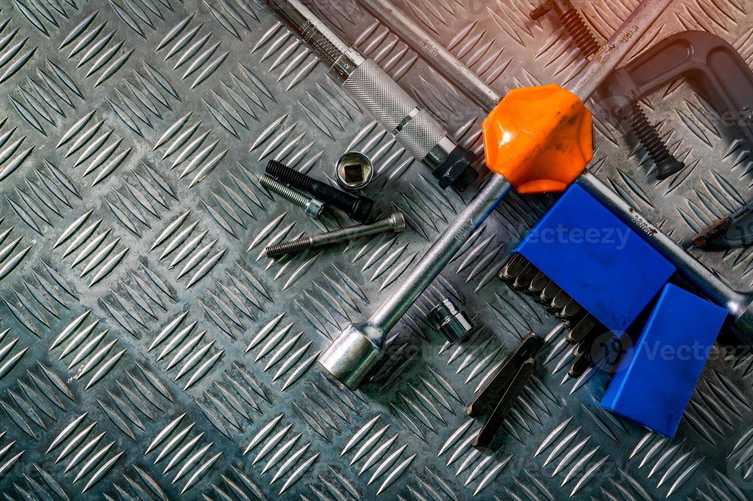 Top view of tools on industrial metal checker plate. Metal checkerplate for anti skid. Nut, bolts, and hex key on metal sheet floor. Silver bump ground with art pattern. Silver texture background. photo