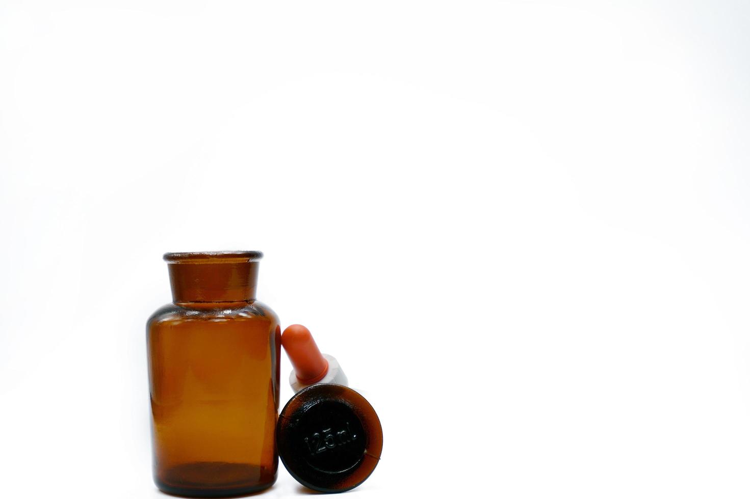Amber glass bottle whit plastic dropper on white background with copy space. Brown medicine bottle. Pharmaceutical industry. Empty drug bottle with blank label. photo