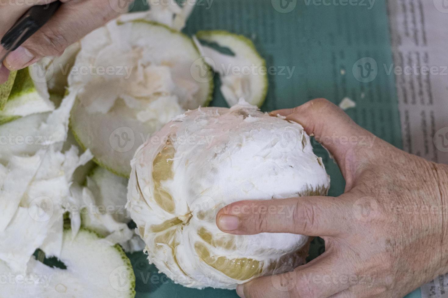 golden women peel pomelo sweet organic tropical fruit half holding on body hand. fresh big yellow orange citrus spit for share. photo