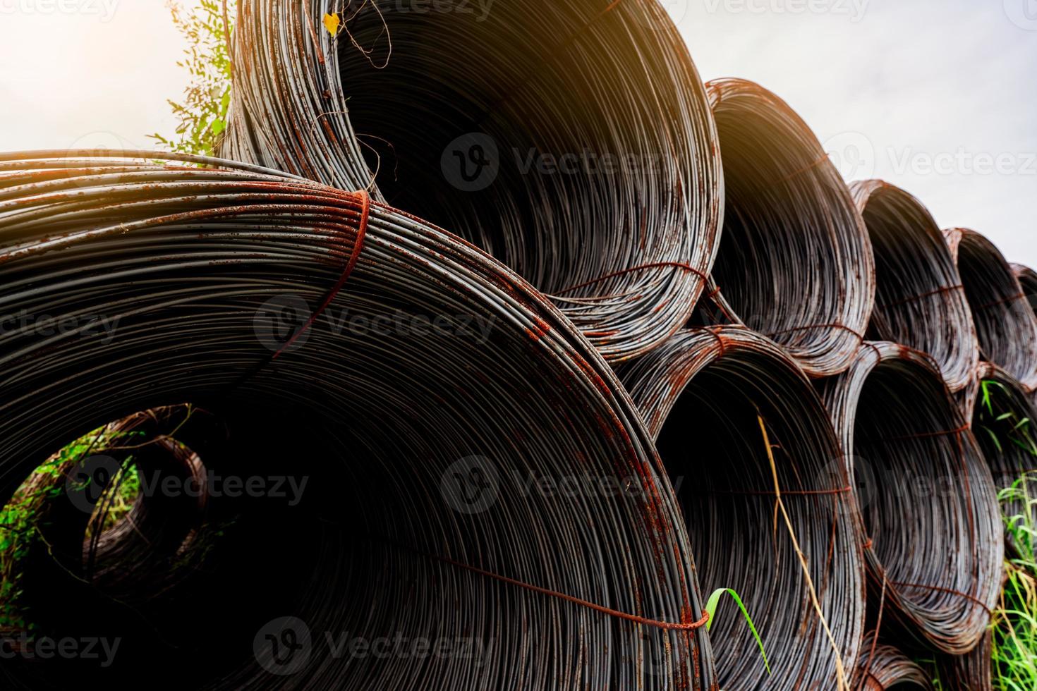 Steel wire coil with sunlight sky. Metal steel reinforced for concrete construction. Iron wire for construction industry. Spool or roll of silver steel wire. Metal materials. Rusty steel wire coil. photo