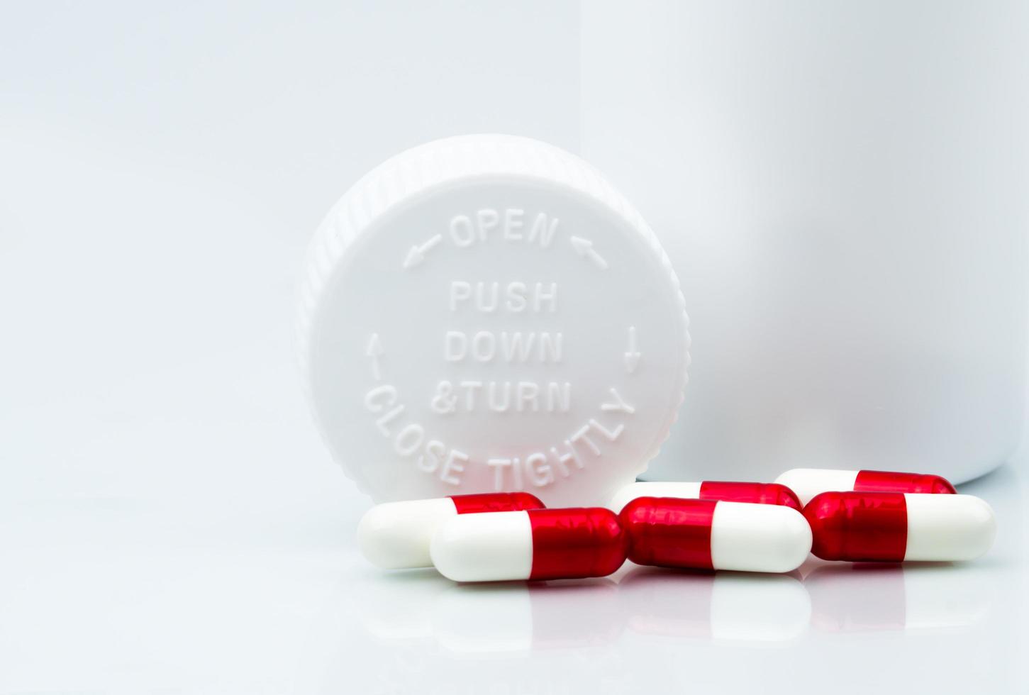 Capsules pills on white background and plastic bottle with blank label and copy space. Childproof packaging. Child resistant pill container. Push down and turn cap. Global healthcare concept. photo