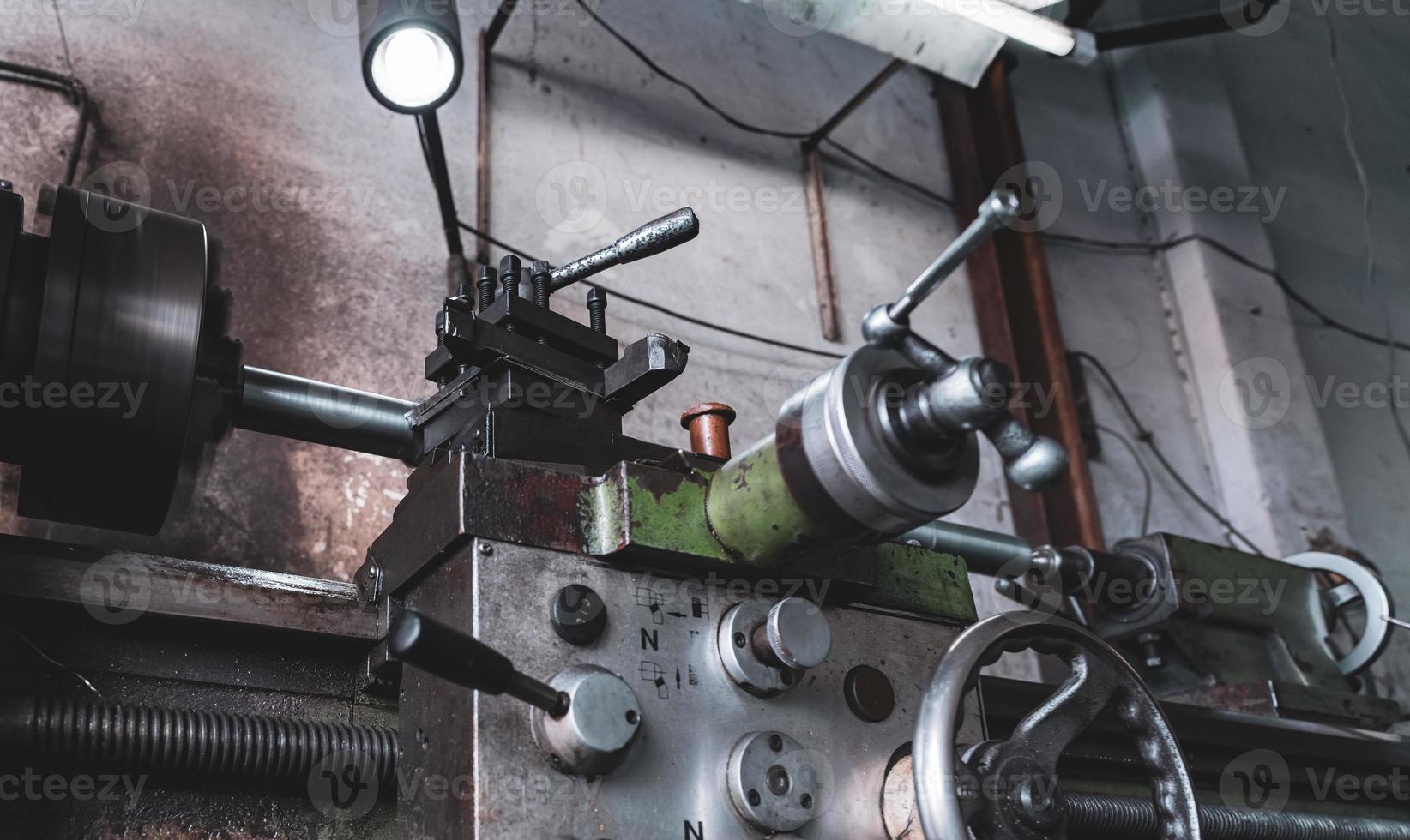 Old lathe machine in factory. Lathe turning machine for metalwork. Heavy machinery manufacturing. Machine for milling metal. Manual lathe machine. Safety in industrial workplace. Steel industry. photo