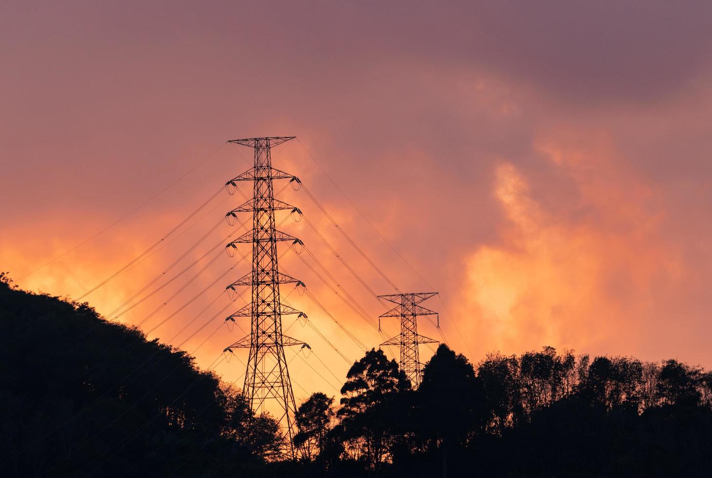 High voltage electric pole and transmission lines in the evening. Electricity pylons at sunset. Power and energy. Energy conservation. High voltage grid tower with wire cable at distribution station. photo