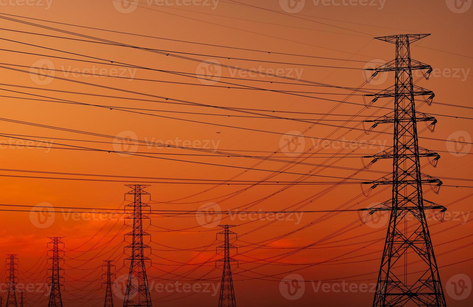 Silhouette high voltage electric pylon and electrical wire with an orange sky. Electricity poles at sunset. Power and energy concept. High voltage grid tower with wire cable at distribution station. photo