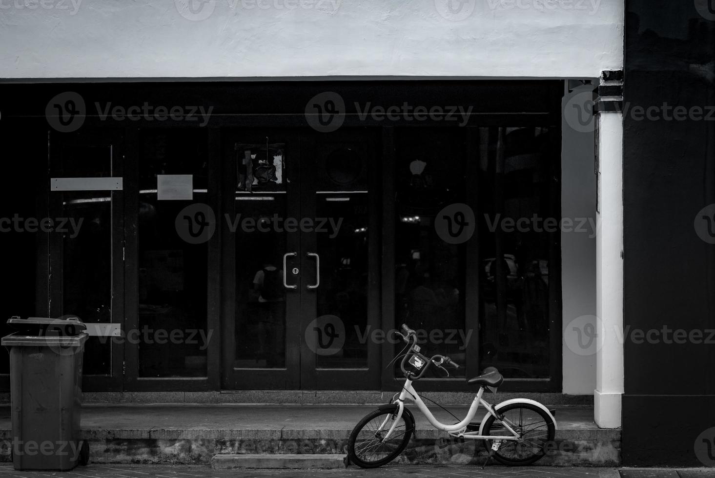 Bike for rent parked on concrete floor in front of office building. Bicycle for city tour. Abandoned bike parked near recycle bin. Eco-friendly transport.  Bicycle for rent by mobile application. photo