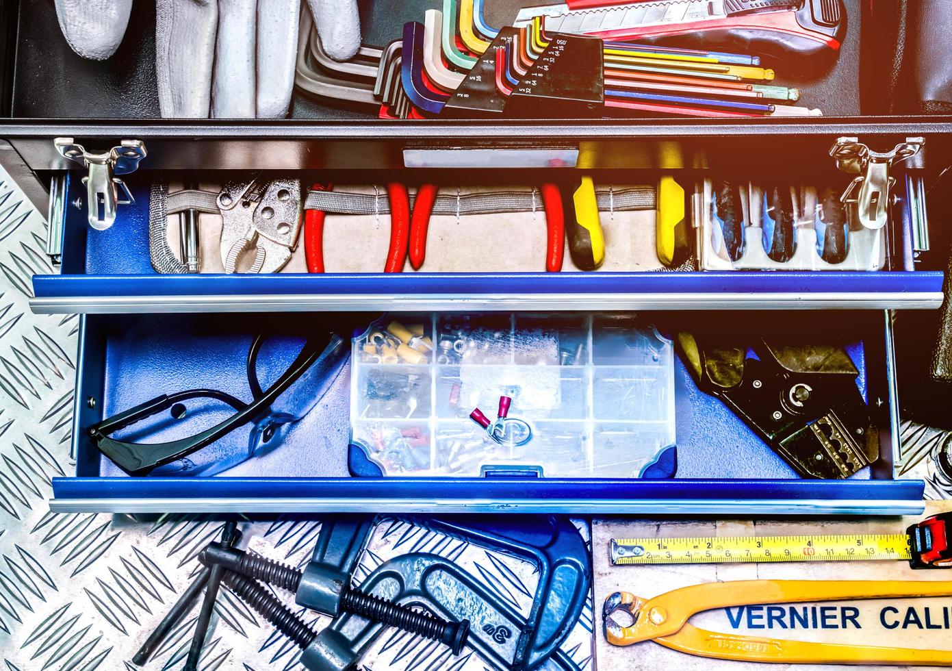 Closeup of tools in box on checkered plate background in workshop. Service tools set. Home building and electrical tools. Plumber hand tools. Technician equipment for repair work. photo