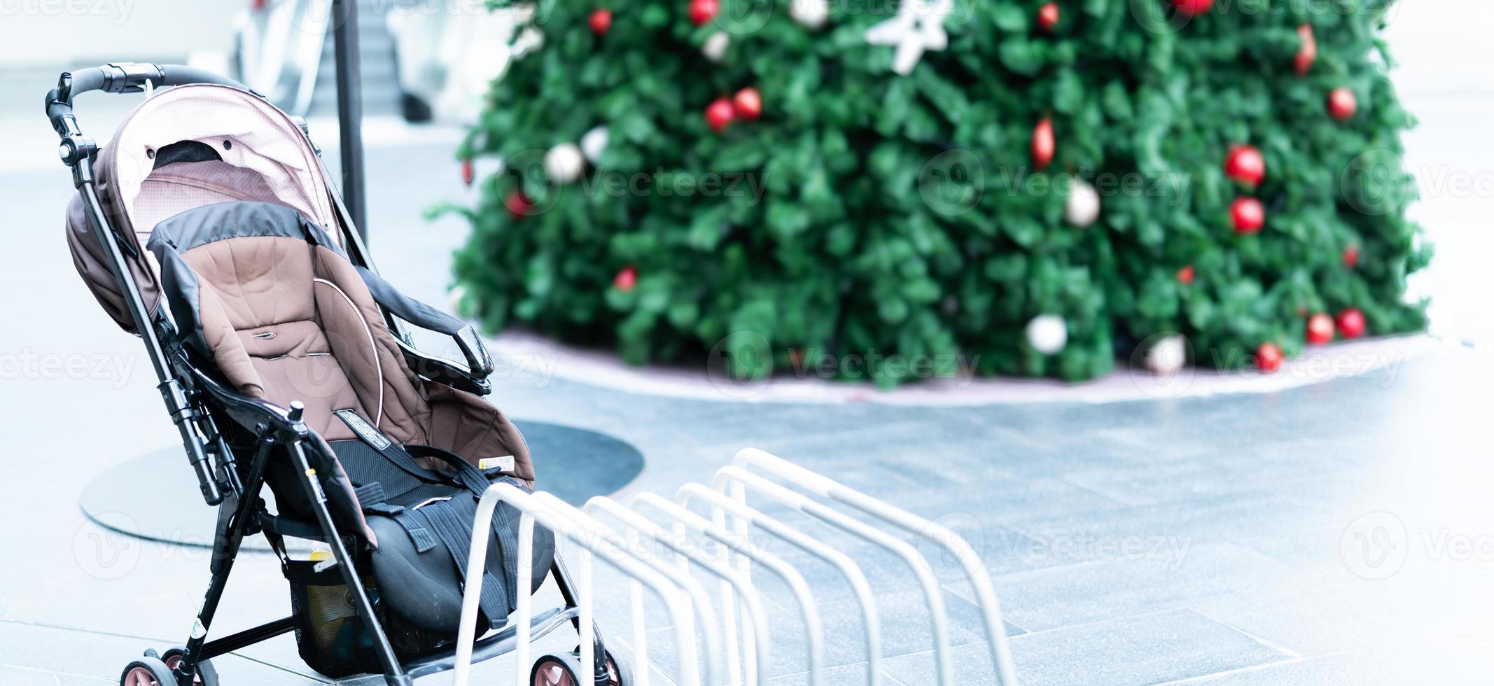 Empty baby stroller parked at outdoor area of shopping mall. Child pram stroller for baby transportation to travel with family. Baby carriage. Activity outside home with child. Abandoned child pram. photo