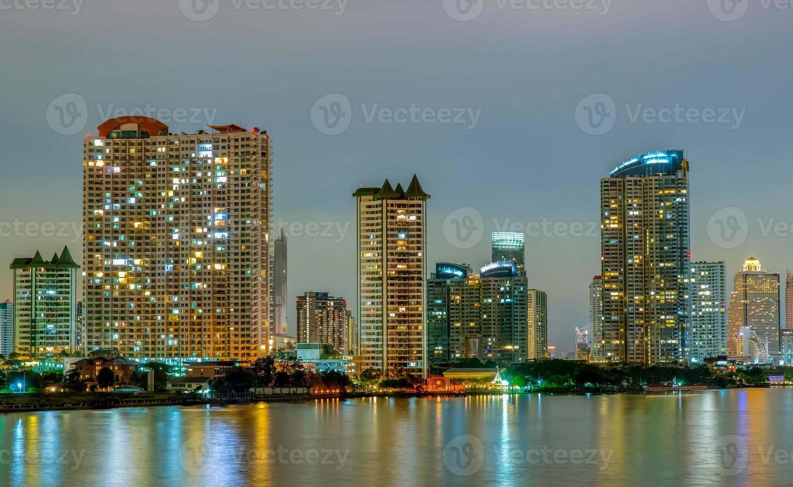 Cityscape of modern building near the river in the night. Modern architecture office building. Skyscraper with evening sky. Night photography of riverfront building. Condominium open light in night. photo