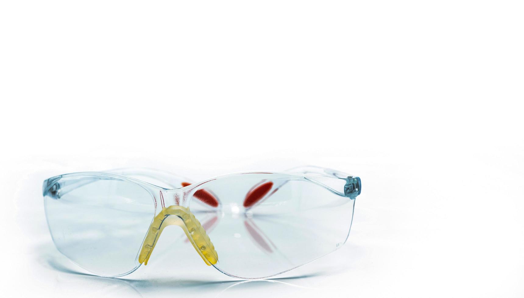Plastic safety glasses isolated on white background. Goggles for protective eye of worker at construction site or in factory. Safety and security tools in work place. Protective eye glasses use in lab photo