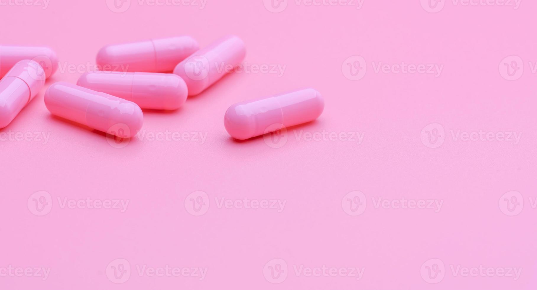 Pink capsule pills on pink background. Vitamin and supplement for healthy skin use in beauty clinic for treatment wrinkle and acne skin. Pharmacy store web banner. Pharmaceutical industry. Happy pill. photo