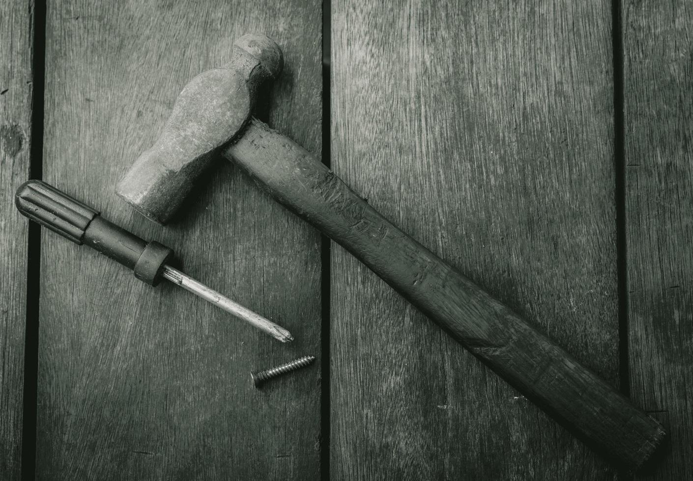 Top view of old hammer, screwdriver and nail on old wooden table. Woodwork tools for fix and repair home. Carpentry tools on an old workbench. DIY tool kit. Equipment for construction in house. photo