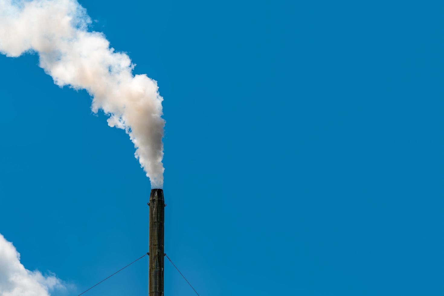 Air pollution from factory. Smoke from chimney of industrial pipe on clear blue sky. Greenhouse effect and global warming problem concept. Bad air quality. Air pollutant emission factors. photo