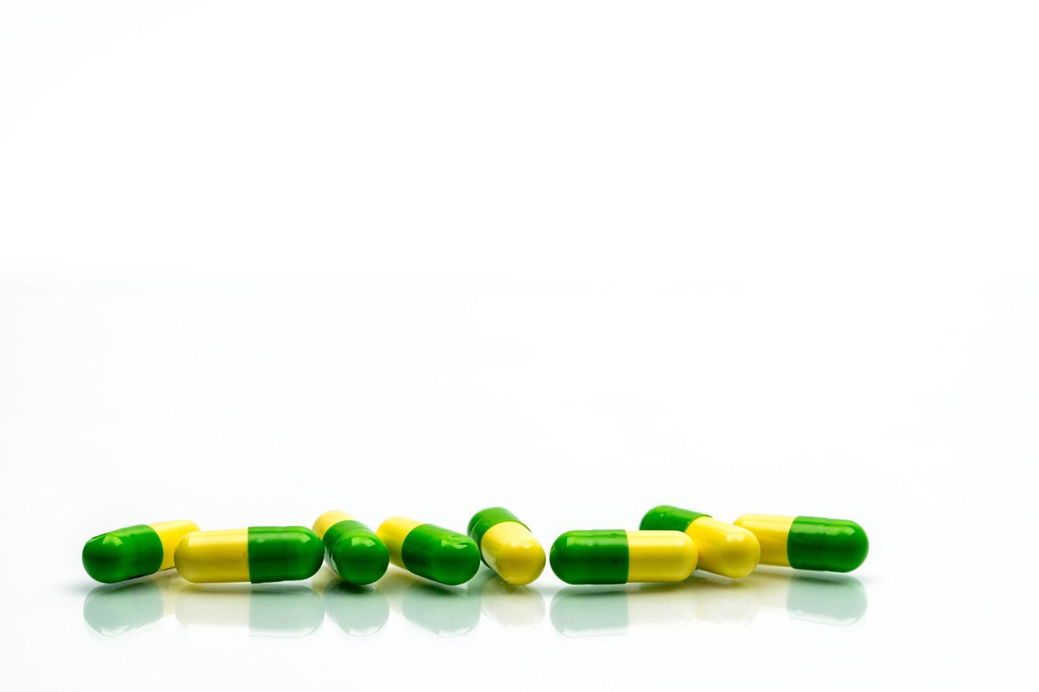 Green, yellow tramadol capsule pills on white background with shadows and copy space. Cancer pain management. Opioid analgesics. Drug abuse in teenage in Thailand. photo