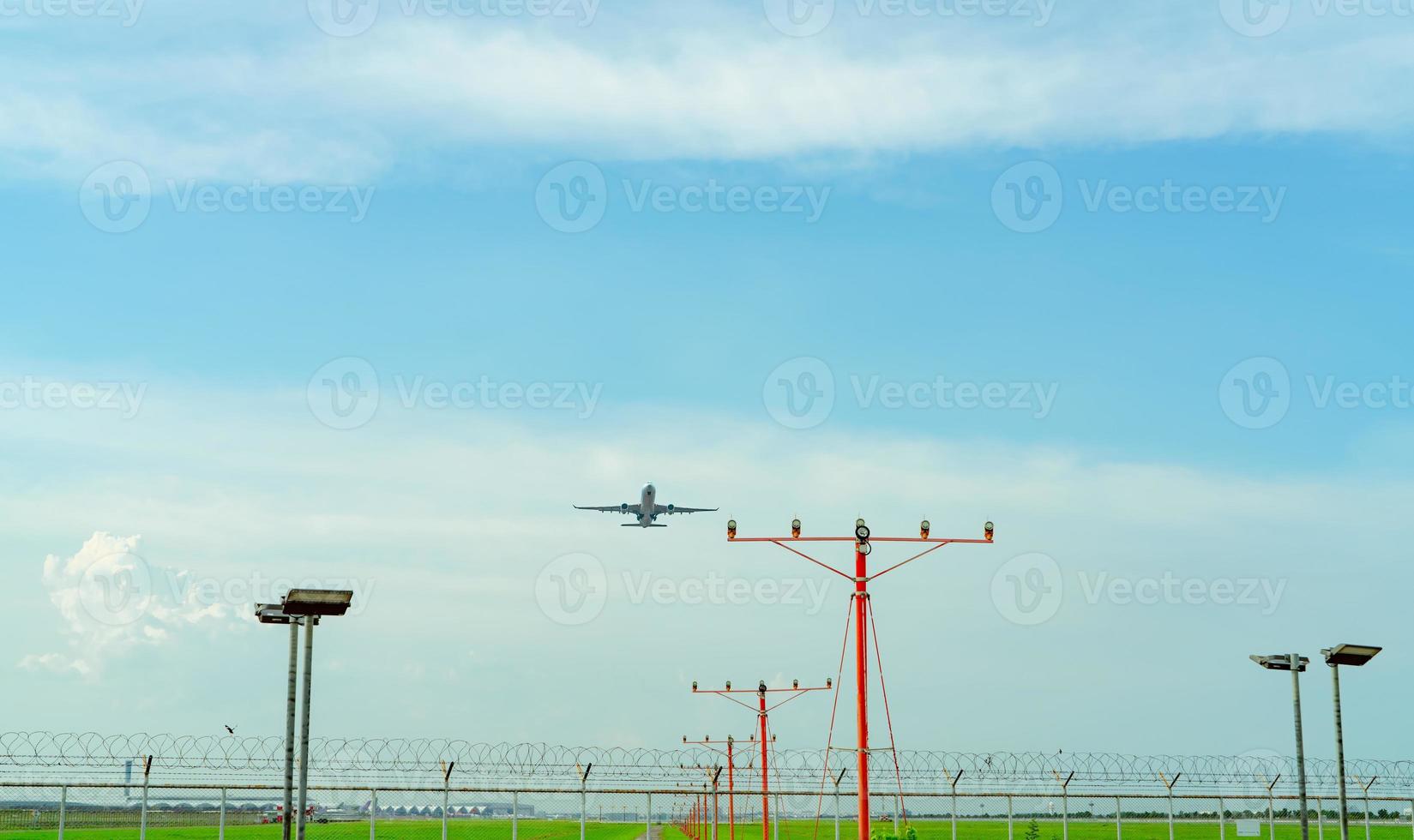 Commercial airplane flying above approach light at the airport. Approach light system concept. Airport runway approach lights. ALS of the airport. Fence for security. Plane take off from the airport. photo