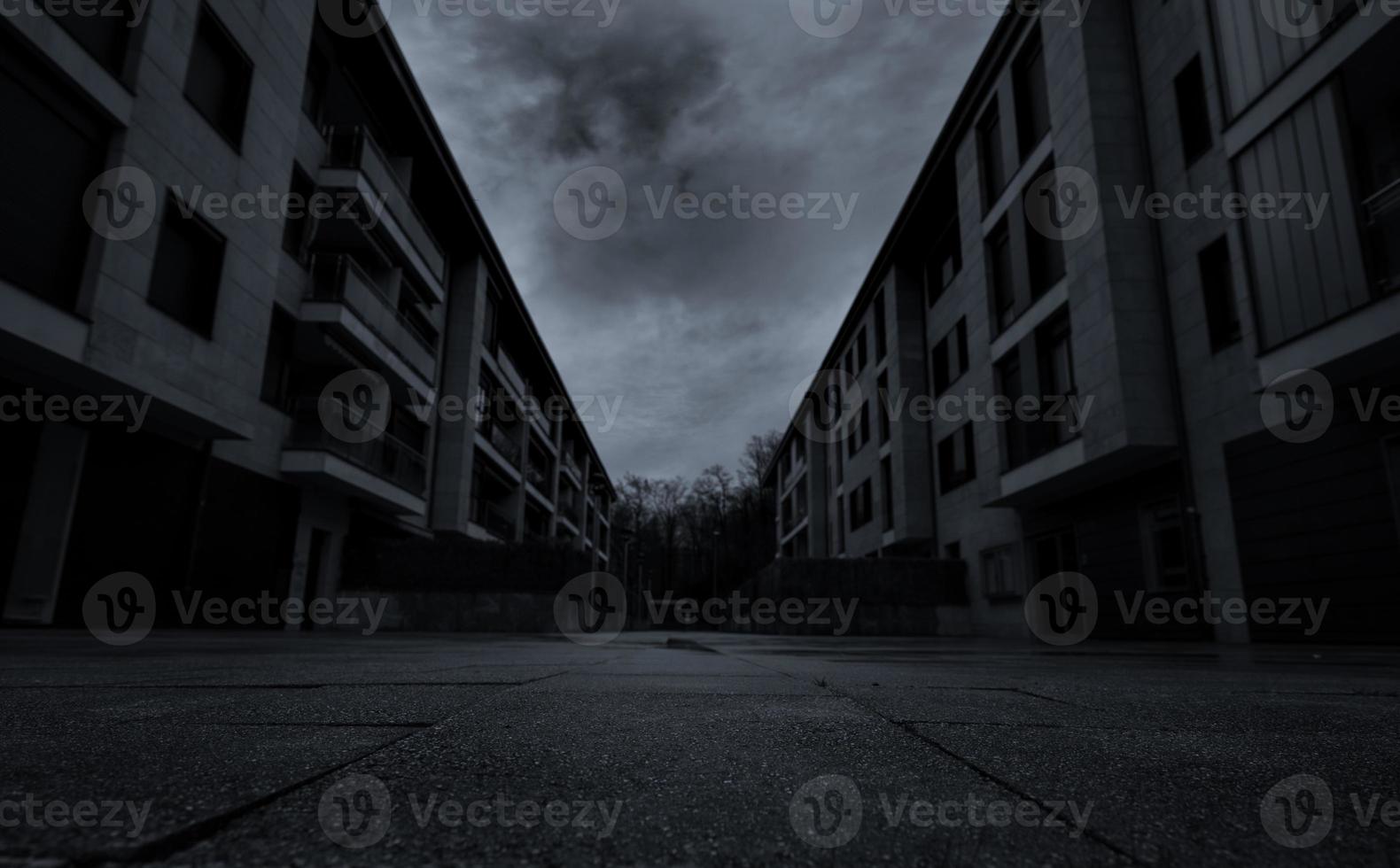 Perspective view of empty road between residential building with dark clouds and sky in the city. No people on urban street. Real estate and property crisis impact of coronavirus or covid-19 concept. photo