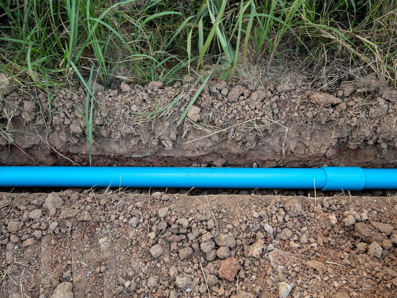 el pequeño tubo de pvc está tendido en la zanja cerca del pavimento