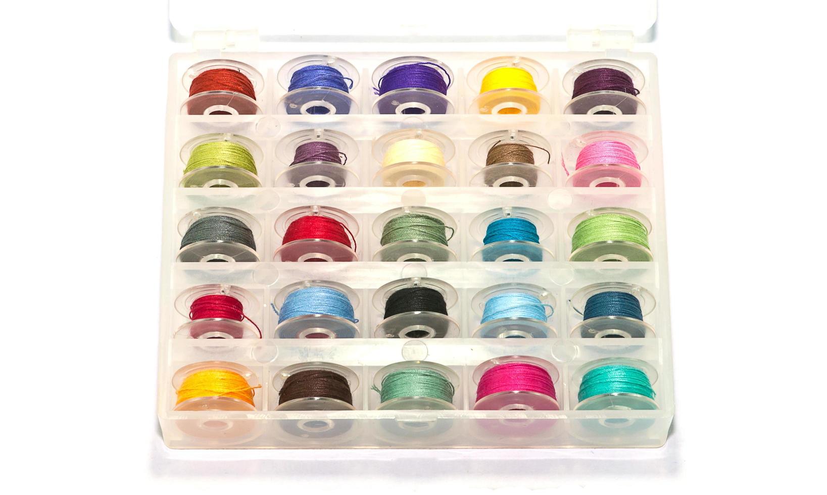 Box of colorful bobbins on white background photo