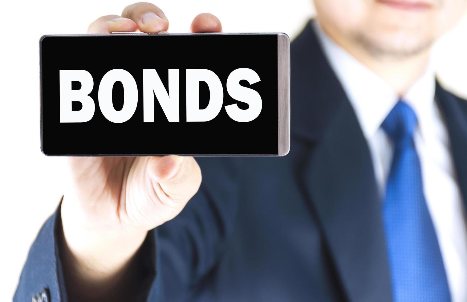 BONDS word on mobile phone screen in blurred young businessman hand over white background, business concept photo