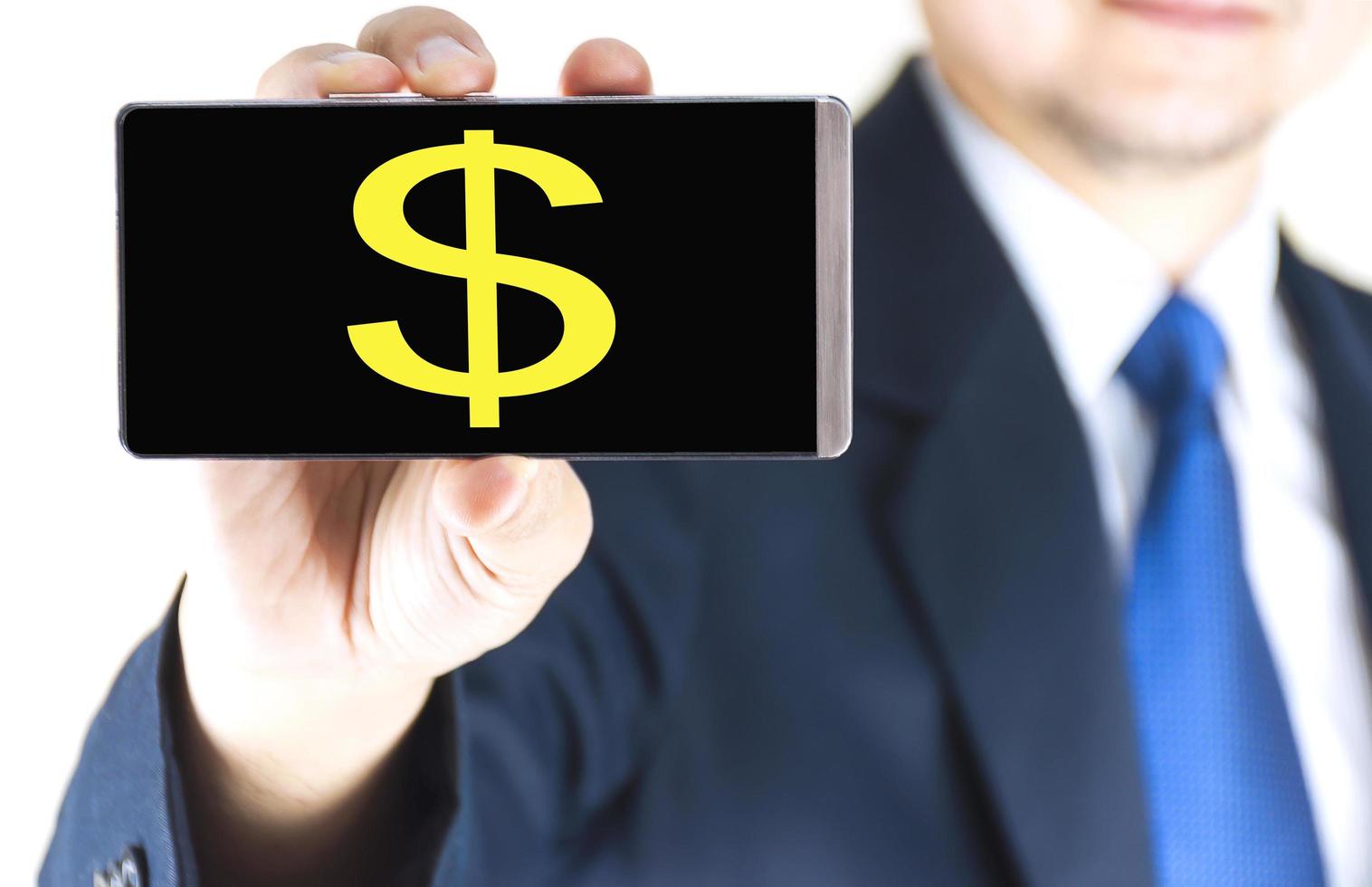 Dollar sign character on mobile phone screen in blurred young businessman hand over white background, business concept photo