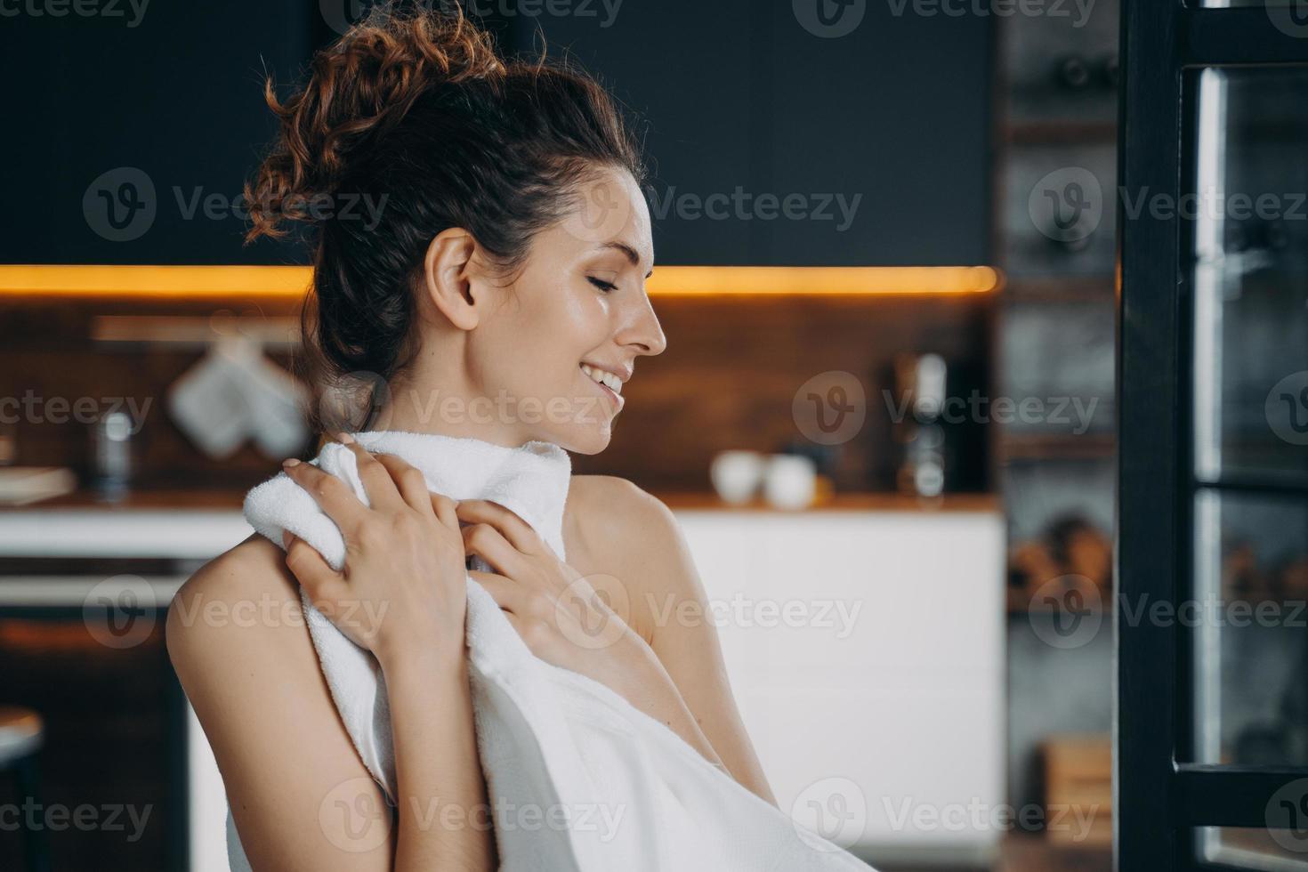 Morning beauty routine. Happy european girl is wiping face with soft towel after washing. photo