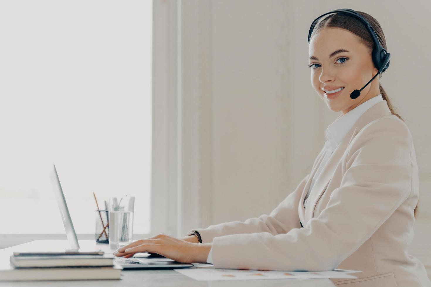 Smiling call center agent in headset consulting client photo