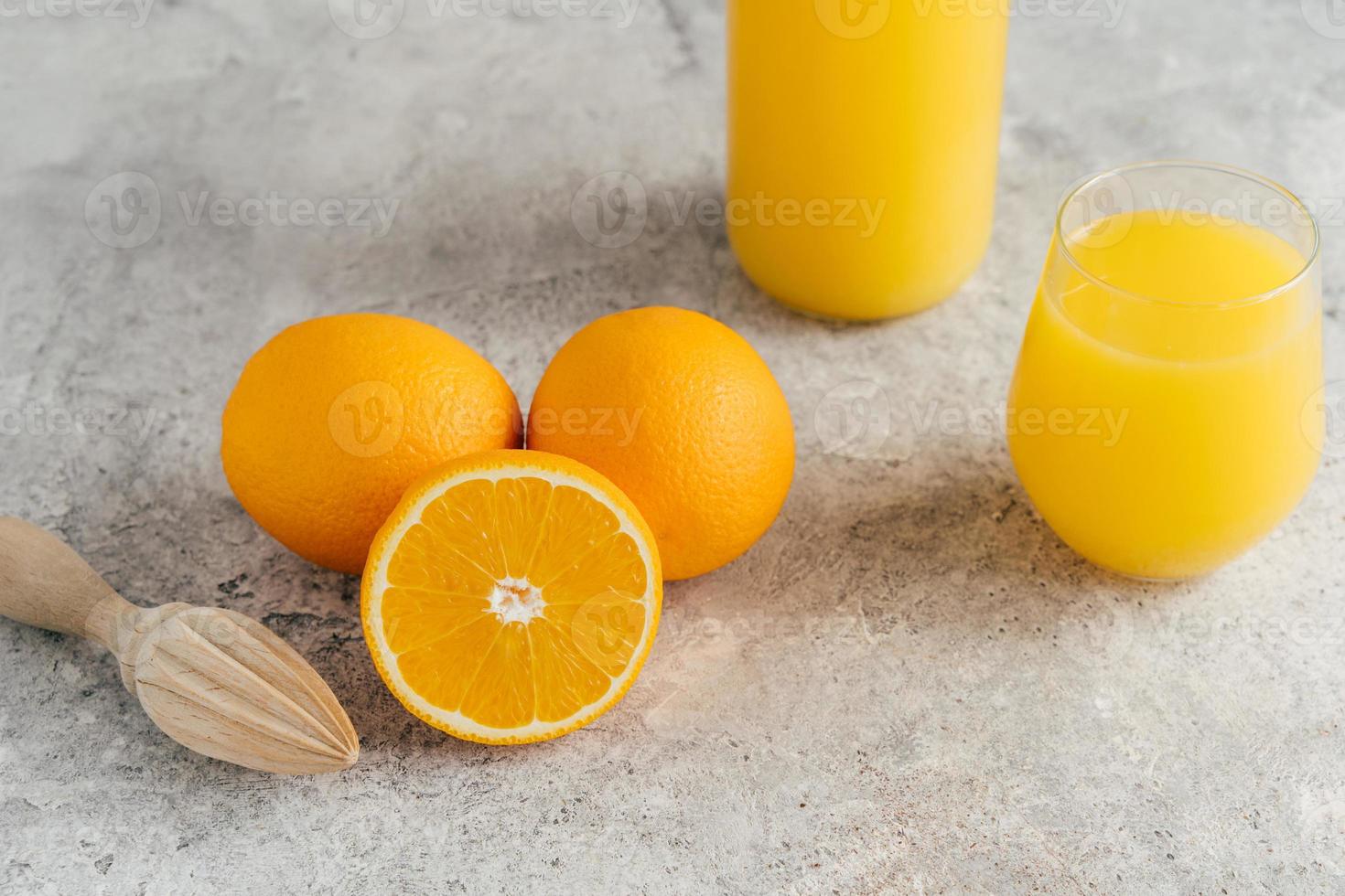 Top view of fresh oranges and fresh orange juice in glass, wooden juicer on white table. Multifruit juice. Fruit drink full of vitamin C photo