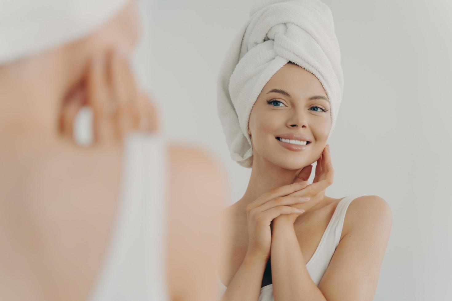 hermosa joven después de la ducha mirándose en el espejo en el baño foto