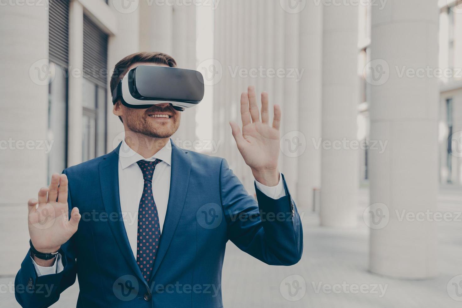 Professional male architect in augmented reality headset gesturing while standing outdoors photo