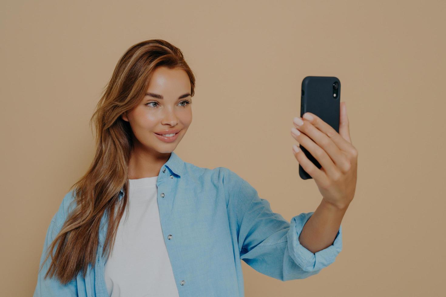 Adorable female model poses for making selfie in studio photo
