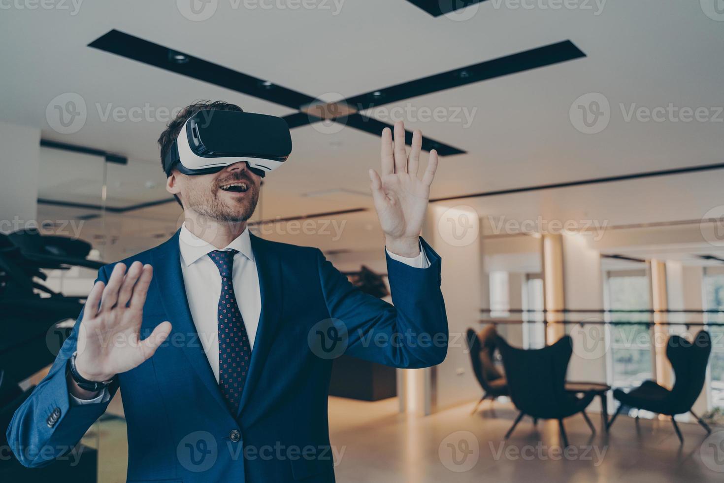 Businessman in futuristic VR headset touches air with his palms immersed in virtual reality photo