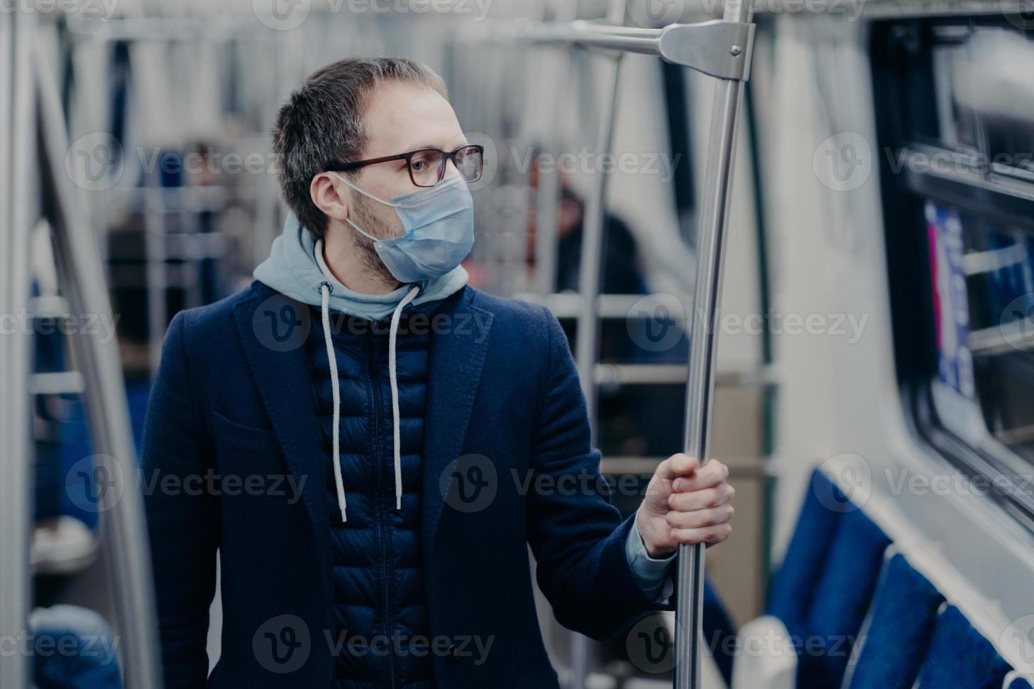 Prevention in public transport, health awareness for pandemic protection. Young man wears medical mask while travels by urban train, protects himself from virus. Covid-19 outbreak in Europe. photo