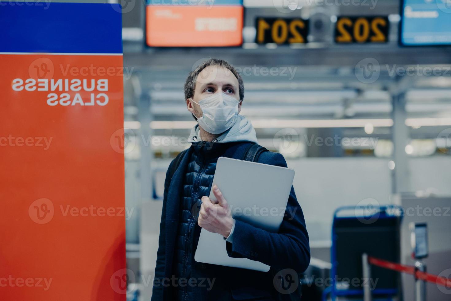 Tourist poses in airport, wants to return home during quarantine and world pandemia, wears protective medical mask against coronavirus, avoids infection and virus spreading. Traveling during outbreak photo