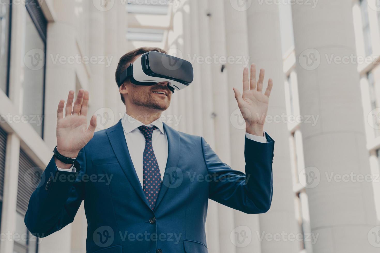 Businessman using VR headset for virtual reality game for work, standing outdoors photo