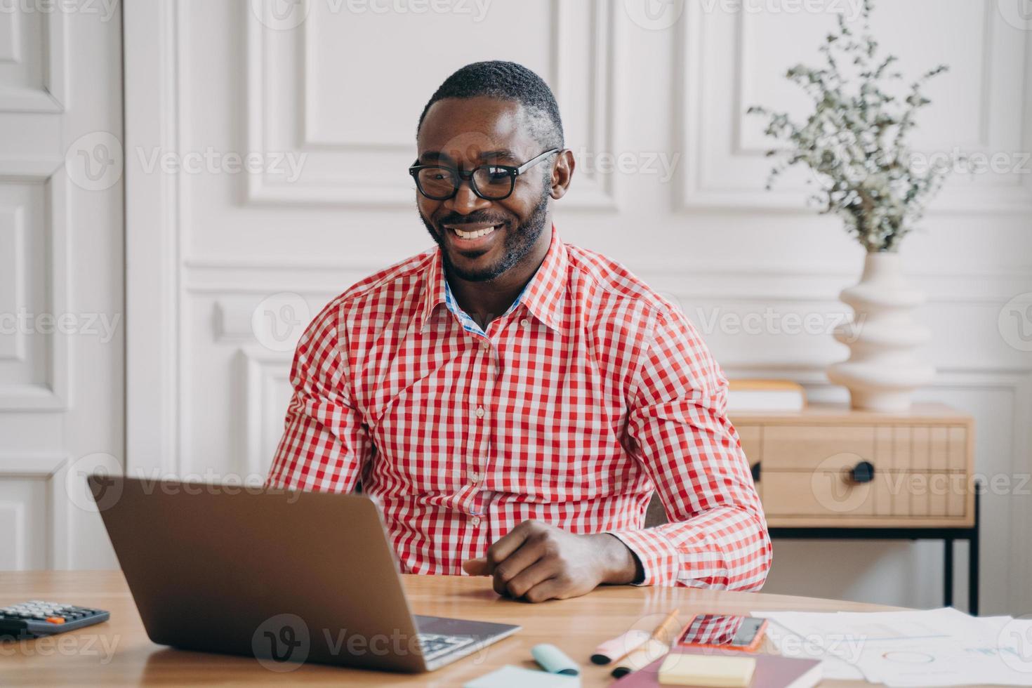 Happy african american man office worker chatting online with business partner via internet photo