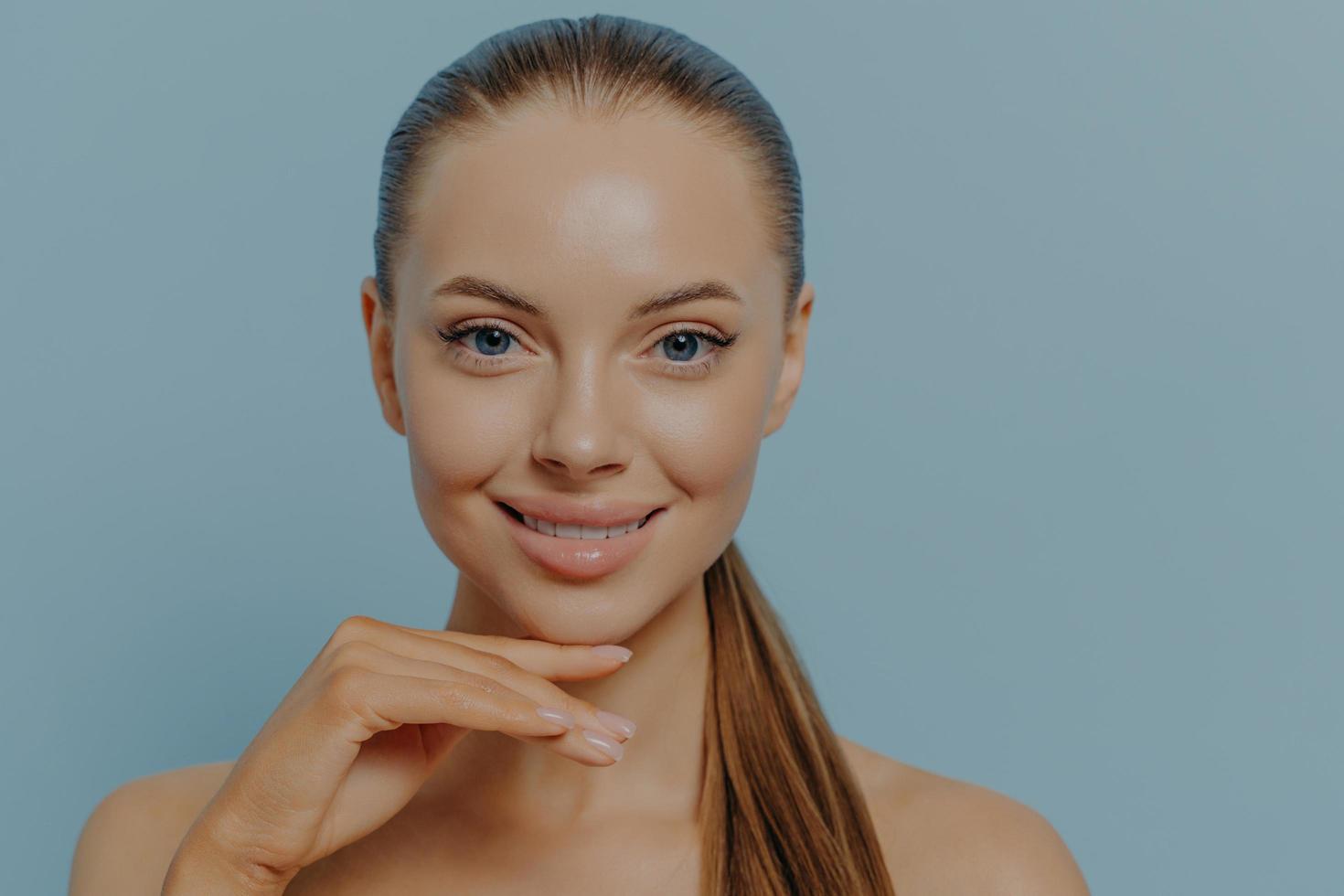 Charming female enjoying her daily skincare routine, touching chin, showing healthy hydrated skin photo