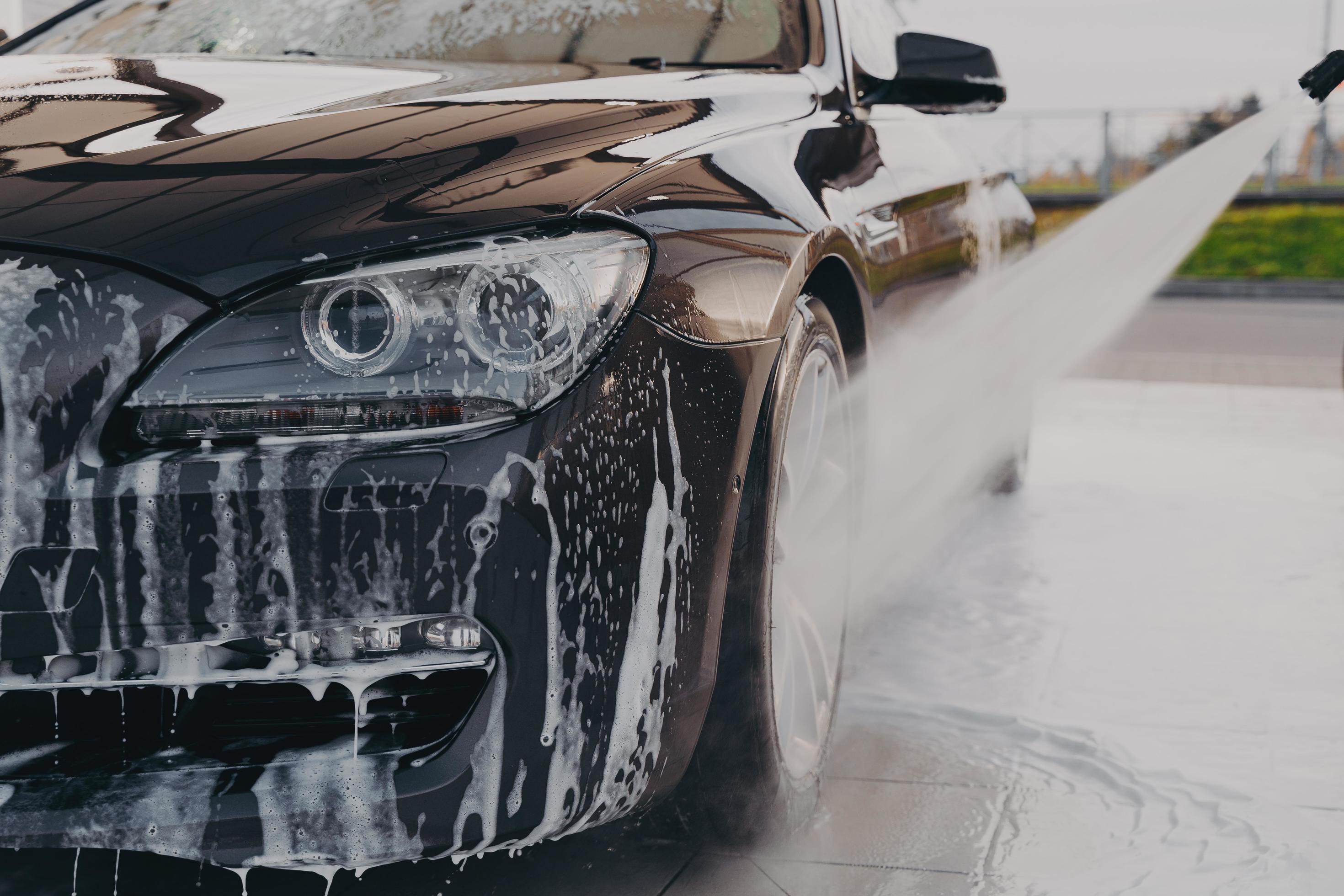 Professional car wash, spraying water from high pressure washer to