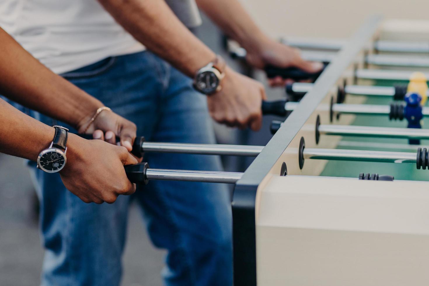 People enjoy playing soccer game, play table football, enjoy recreation time. Mini game. Leisure and activities concept. Entertainment concept photo