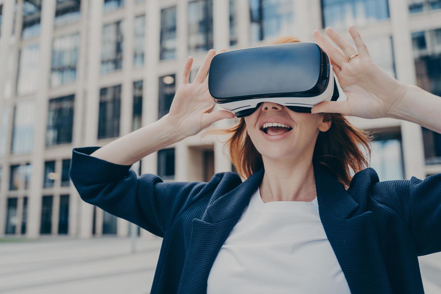 Excited businesswoman exploring virtual reality with VR headset outdoors photo