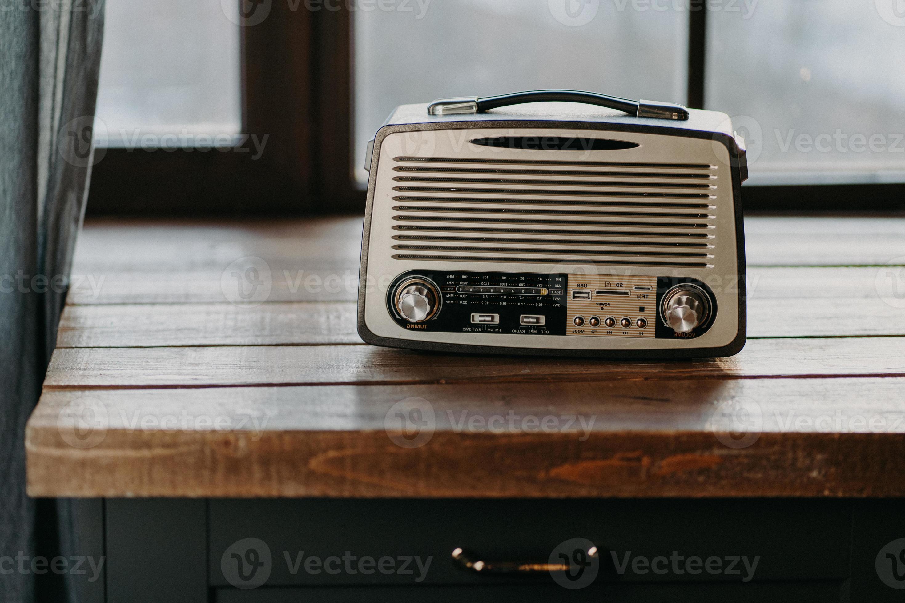 Retro vintage radio on wooden table surface near window. Back to 80s