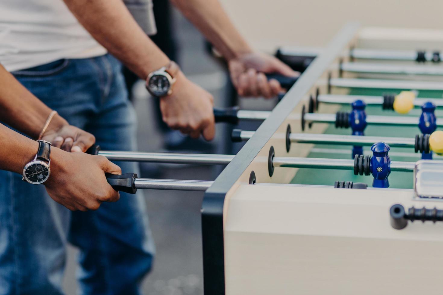 Table football game or soccer. Men play kricker together during weekend as have spare time, enjoy recreation time. Heated people. photo