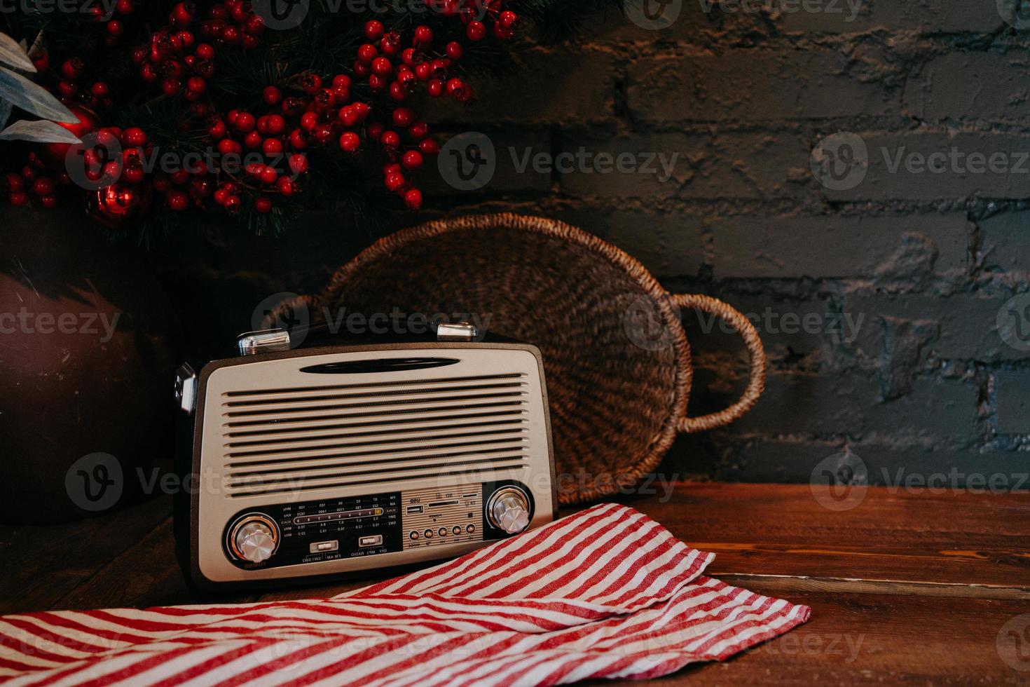 Retro radio on wooden table with wicker basket and floral decor. Vintage style. Antique old broadcast radio receiver on rustic background. photo