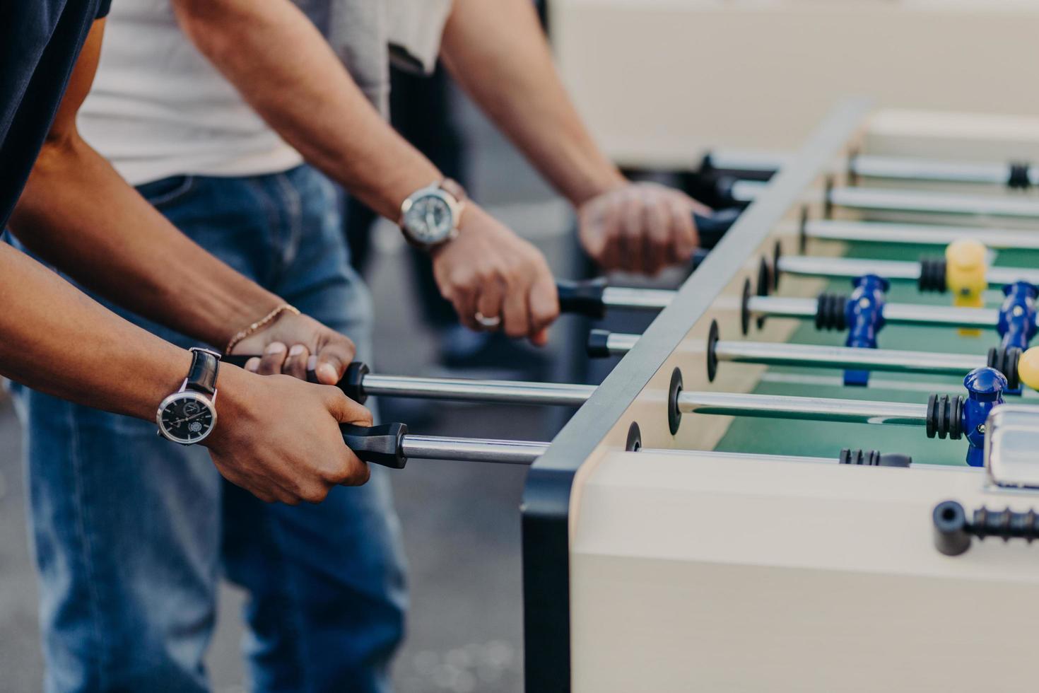 Cropped view of males hands play table football, enjoy recreation or leisure time during holidays, spend free time in bar. Competition concept photo