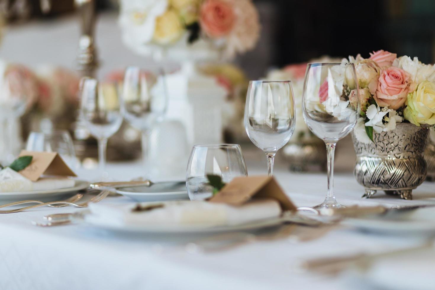 hermosa mesa servida con cristalería y cubertería, decorada con flores, preparada para el evento festivo. ocasión especial celebrada en restaurante o cafetería de lujo. concepto de ajuste de la mesa. mesa de boda foto