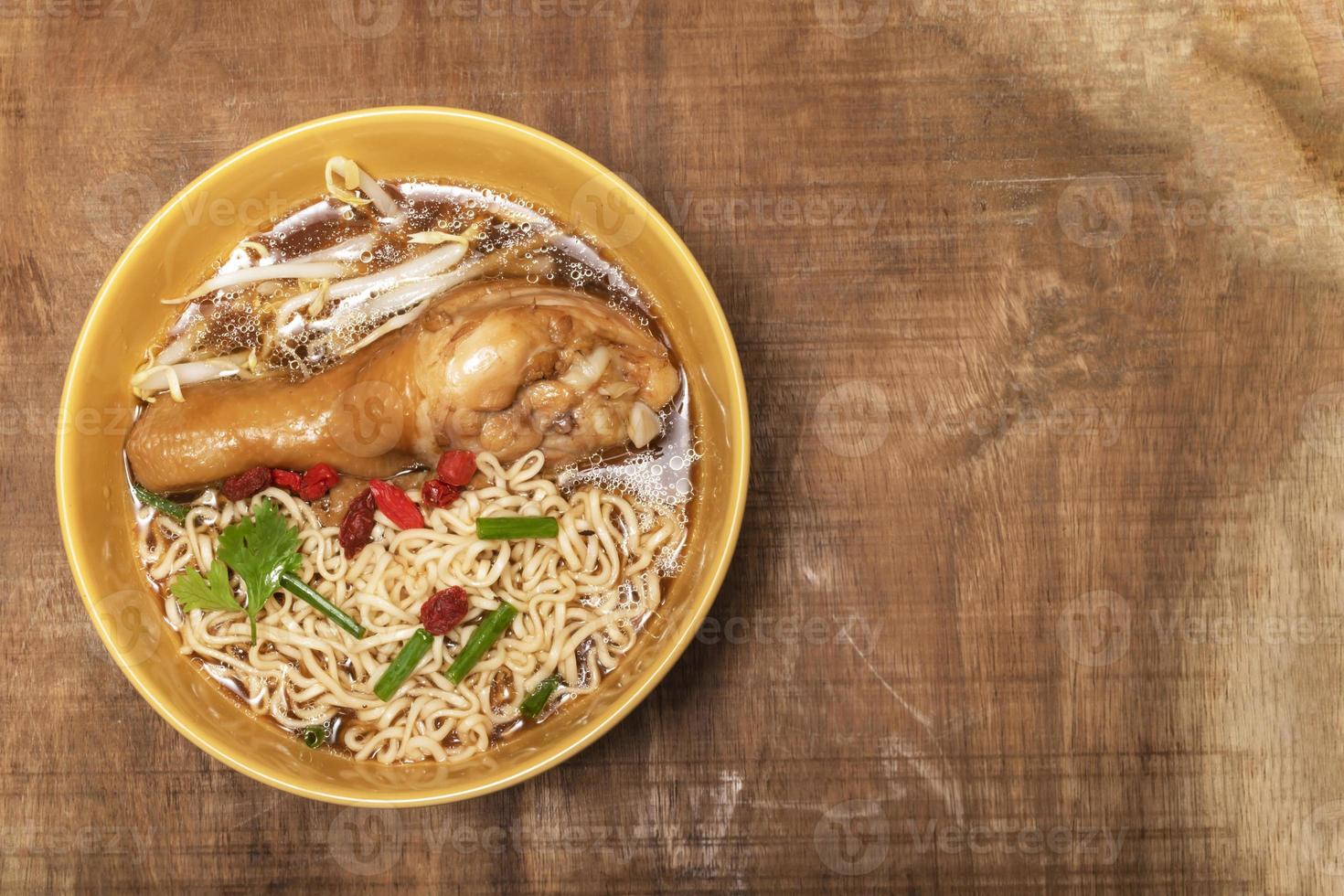 Noodles soup in bowl has chicken on wood table. photo