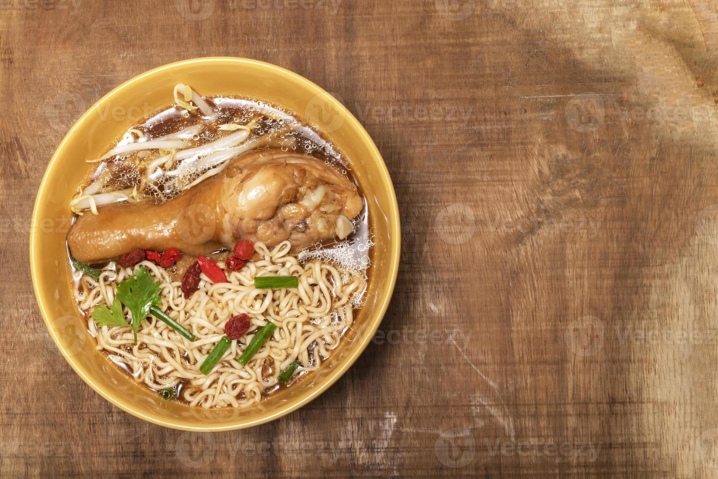 la sopa de fideos en un tazón tiene pollo en la mesa de madera. foto