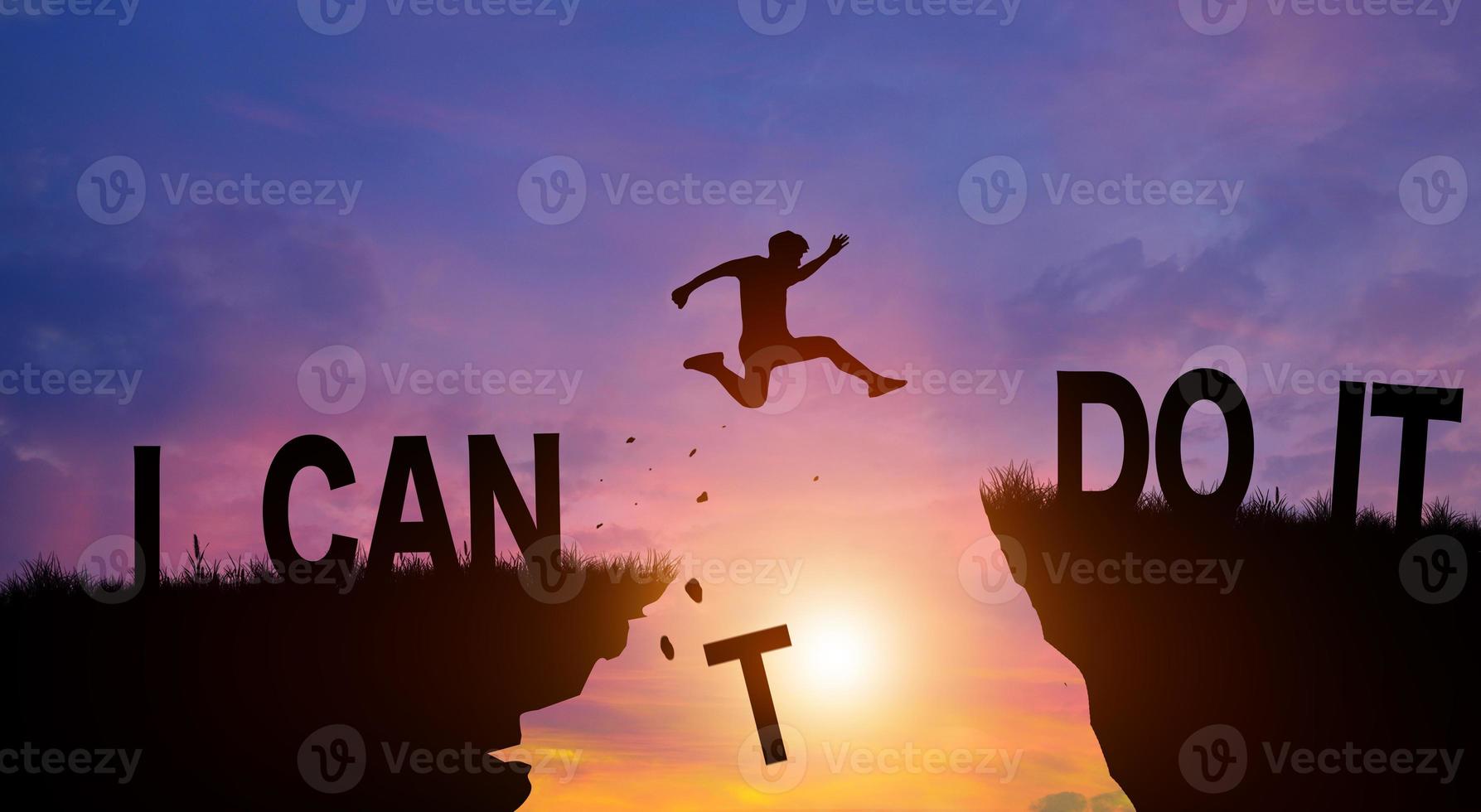 Silhouette man jumping over the cliffs with I can do it word in sunlight. Never give up, Good mindset Concept. photo